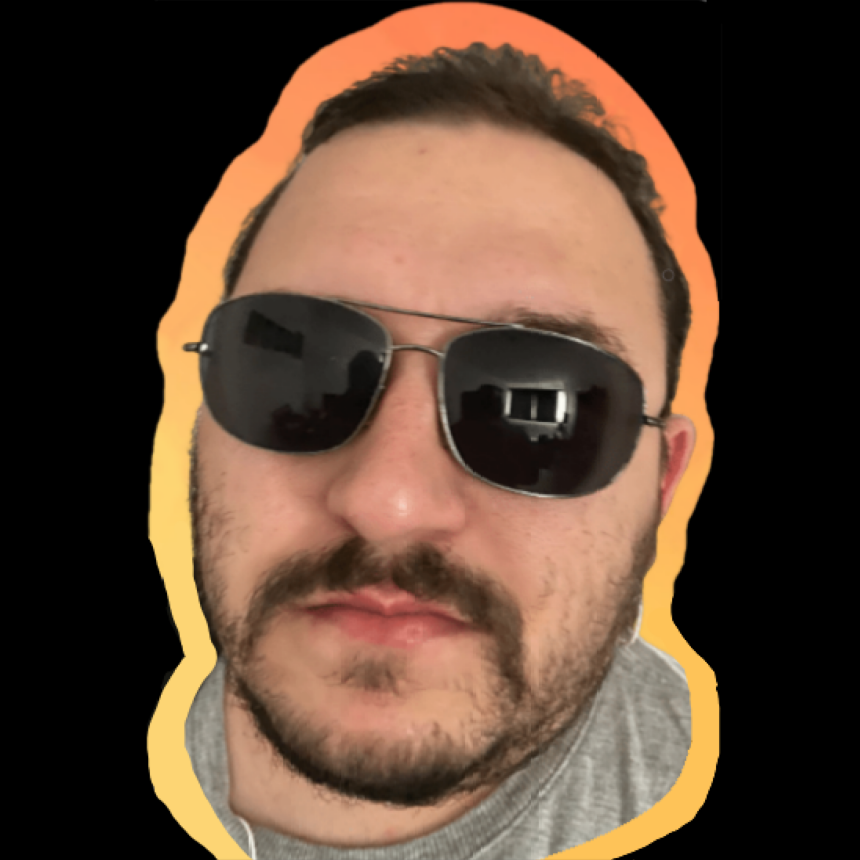 Foto do rosto de Sidney Andrade, em um círculo de fundo preto. A foto tem contorno em degradê do amarelo ao laranja.
Sidney é um homem com cerca de 35 anos, pele bege clara e cabelos castanho claro. Ele tem testa ampla e rosto redondo. Seu nariz grande de ponta afinada e seus lábios são finos e rosados. Ele tem barba curta e bigode mais destacado, que se une à barba pelas laterais de seu queixo redondo. 
Usa óculos escuros arredondados, com armação dupla no nariz, camiseta cinza e tem a cabeça levemente inclinada para o ombro esquerdo e levantado.